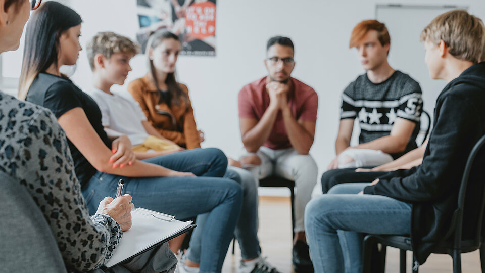 Personen sitzen im Kreis zusammen