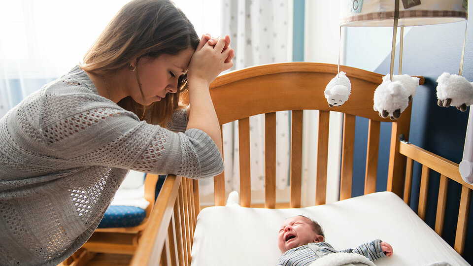 Erschöpfte Mutter vor ihrem schreiendem Baby