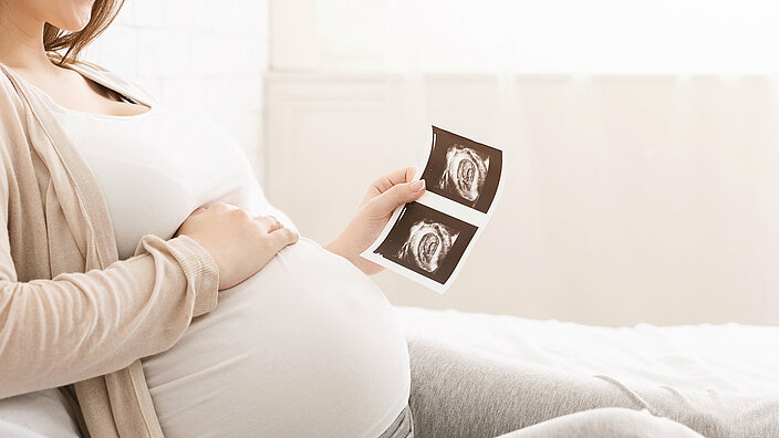 Schwange Frau betrachtet Ultraschallbild