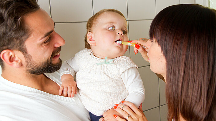 Eltern putzen ihrem Kind die Zähne