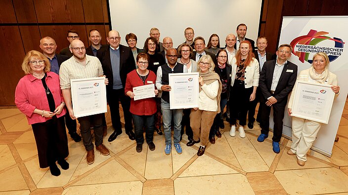 eine Gruppe von Menschen hält den niedersächsischen Gesundheitspreis in der Hand