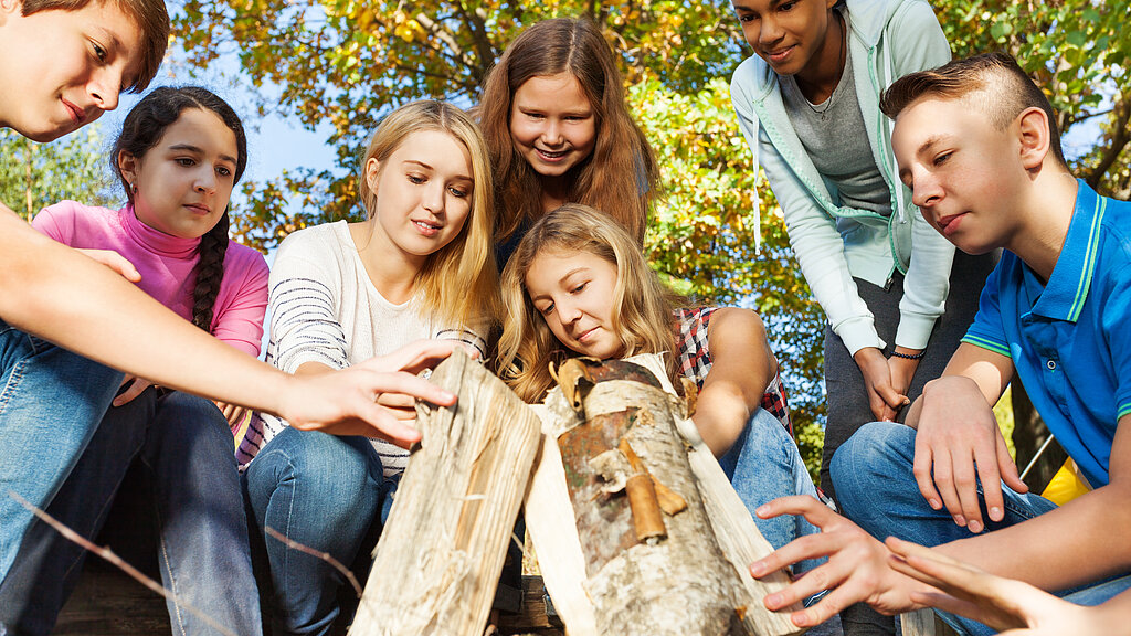 Kinder und Jugendliche stapeln zusammen ein Lagerfeuer auf