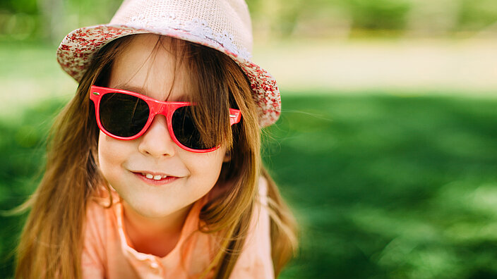 Ein Kind mit einer Sonnenbrille und einem Hut