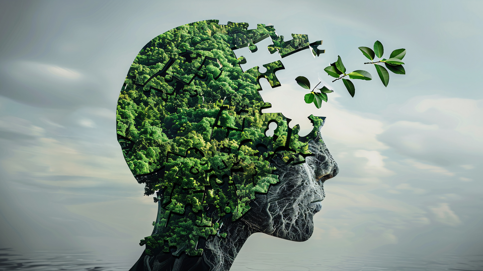 Die Silouhette eines Kopfes, der aus zusammengsetzten Puzzlestücken mit Baum-Motiv besteht. Aus dem Kopf fliegen Blätter.