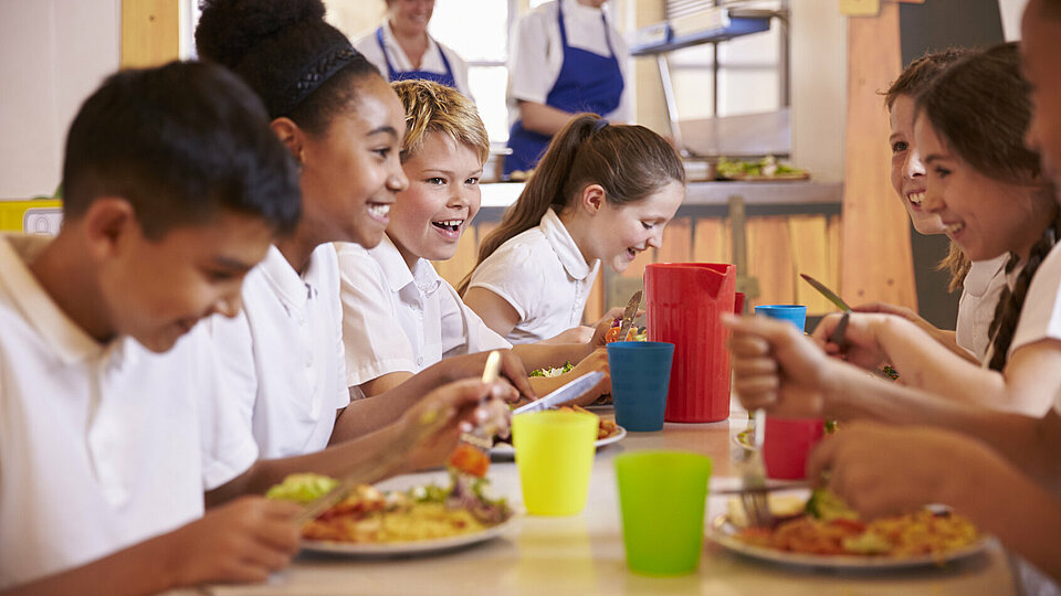 Nahaufnahme von Grundschulkindern an einem Tisch in der Schulcafeteria