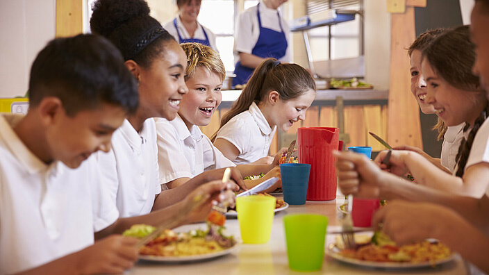 Nahaufnahme von Grundschulkindern an einem Tisch in der Schulcafeteria